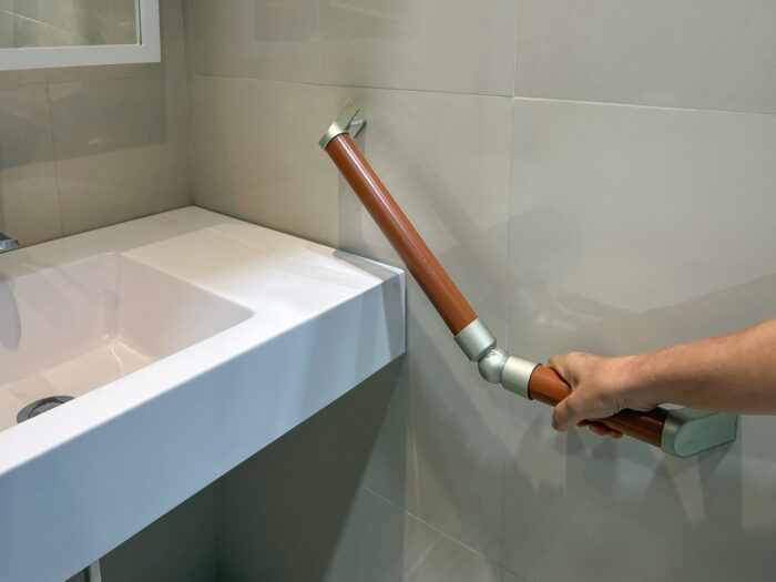 Someone holding a grab rail in a bathroom