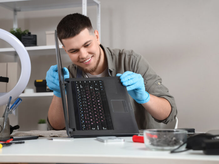Male technician repairing laptop at table in service center