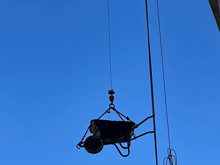 A wheelbarrow containing things being winched up into the tower during works