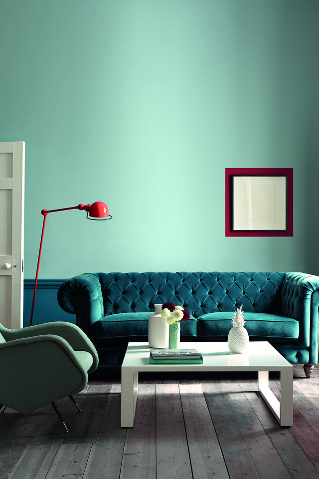 Turquoise blue living room with pincushion sofa, red floor lamp and white coffee table